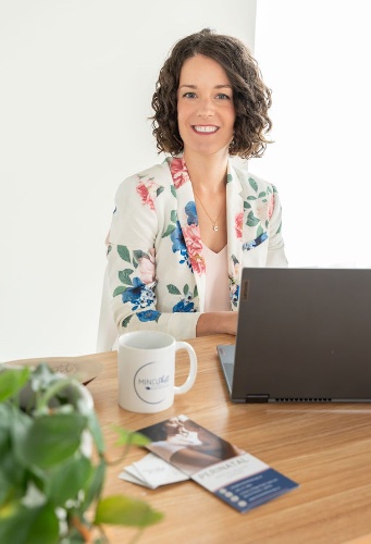 Therapist welcoming clients at her desk with a laptop and a mug